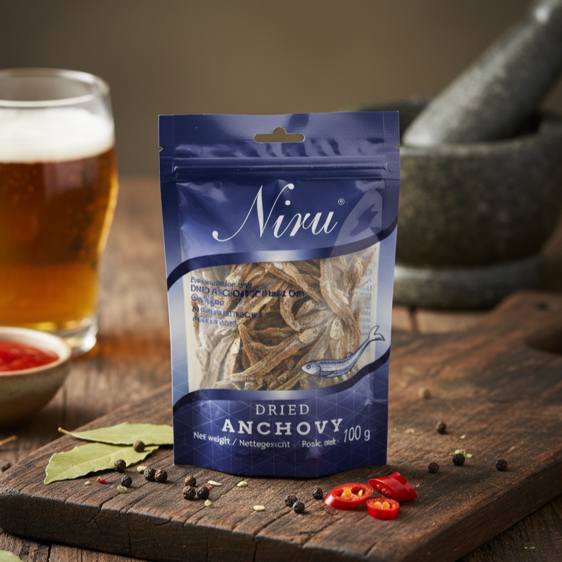 Niru dried anchovy package on a wooden board with a glass of beer and ingredients in the background.